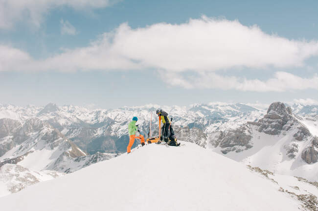 Vista lateral de atletas irreconocibles hablando sobre nieve durante un viaje en Pico Aunamend en los Pirineos Montañas de Navarra España - foto de stock