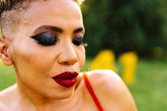 Close up retrato da moda de meia-idade étnica feminina em vermelho desgaste com corte de cabelo moderno e olhos fechados durante a festa de aniversário — Fotografia de Stock