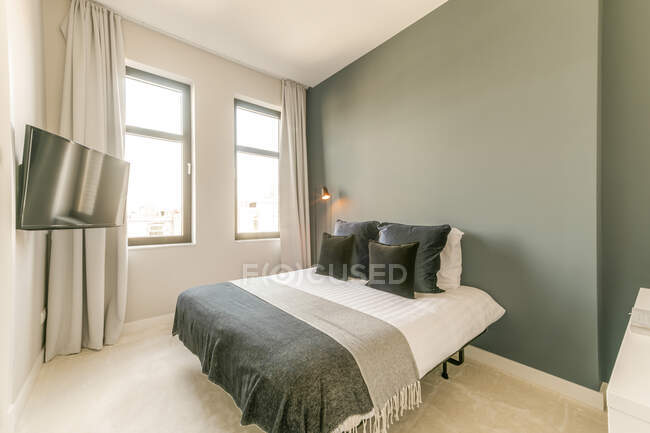 Interno di camera da letto contemporanea con letto con morbidi cuscini posizionati vicino alla finestra in appartamento in stile minimale — Foto stock