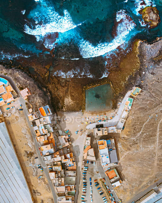 Breathtaking drone view of rooftops of buildings in settlement located on coast near blue sea — Stock Photo