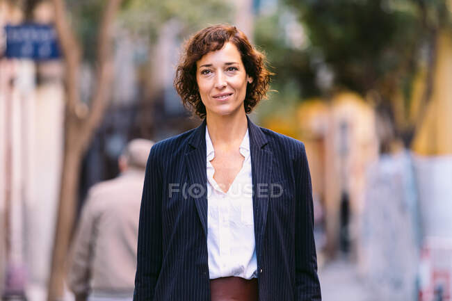 Positive female in classy clothes walking on the street smiling looking away — Stock Photo