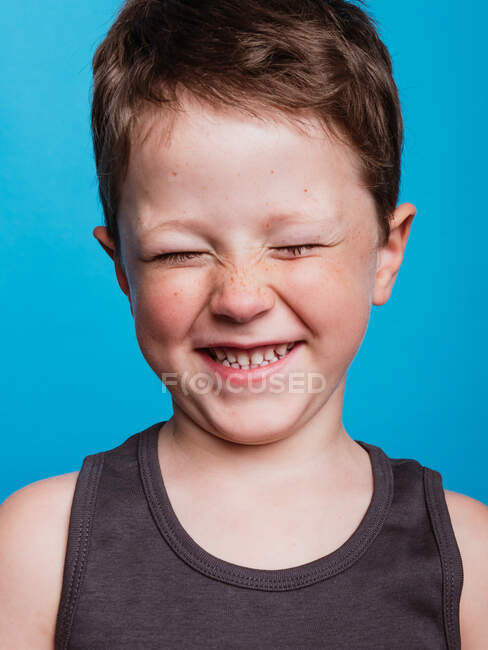 Content adorable preteen boy with closed eyes on bright blue background in studio — Stock Photo