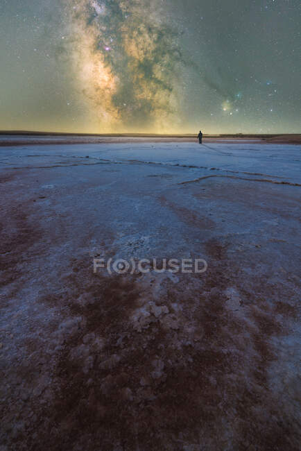 Silhouette di esploratore in piedi nella laguna di sale asciutto sullo sfondo del cielo stellato con la Via Lattea incandescente di notte — Foto stock