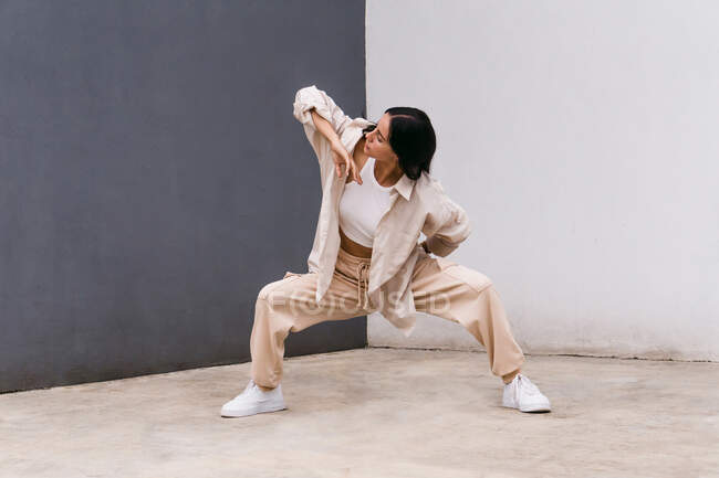 Danseuse talentueuse se déplaçant et dansant près d'un mur de béton en zone urbaine en ville — Photo de stock