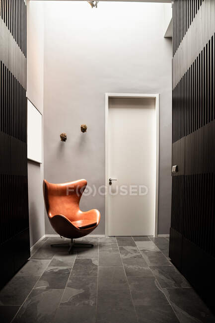 Vue en perspective de l'intérieur du couloir avec des murs gris rayés et une chaise brune placée près de la porte d'entrée — Photo de stock