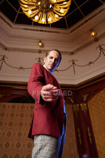 From below of classy adult male theater artist in burgundy jacket and with makeup pointing at camera and looking with question and arrogance — Stock Photo