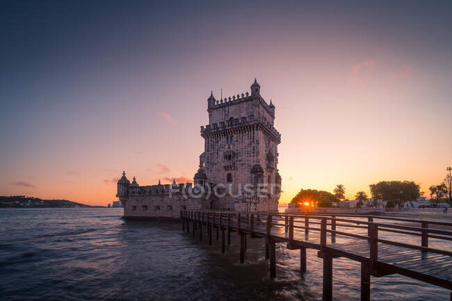 Quai étroit situé près de la célèbre tour Belem sur la rive du Tage contre un ciel nuageux au coucher du soleil à Lisbonne, Portugal — Photo de stock