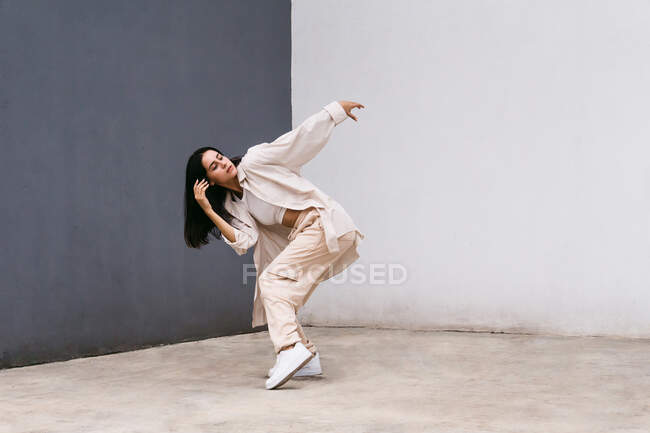 Dançarina feminina criativa de comprimento completo em roupas brancas dançando na rua da cidade durante a performance — Fotografia de Stock