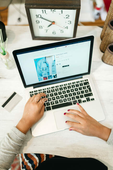 Von oben von Frauen, die Netbook beim Online-Shopping benutzen, während sie zu Hause mit Plastikkarte am Tisch sitzen und Waren auswählen — Stockfoto