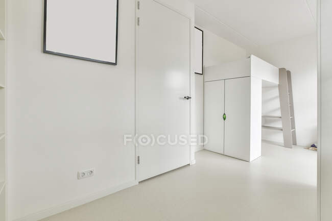 Letto a castello bianco con armadio posto in angolo della moderna camera in stile minimalista con pareti bianche decorate con cornici mockup — Foto stock
