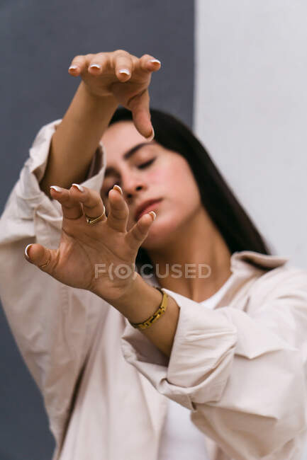 Tranquil graceful woman reaching out hands towards camera while dancing in city street with closed eyes — Stock Photo