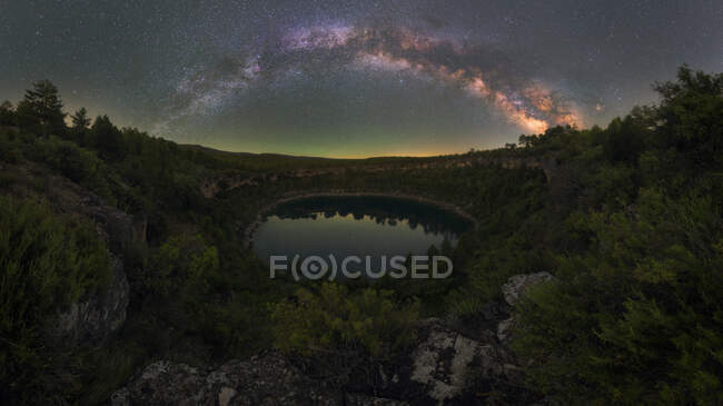 Pintoresca vista de la laguna reflejando árboles creciendo en montes bajo el cielo estrellado en Cuenca España - foto de stock