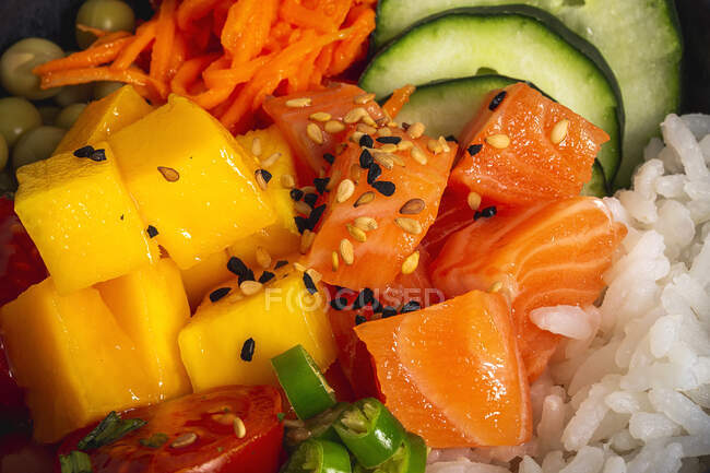 High angle of Asian poke with salmon and rice with assorted vegetables served in bowl on table in restaurant — Stock Photo