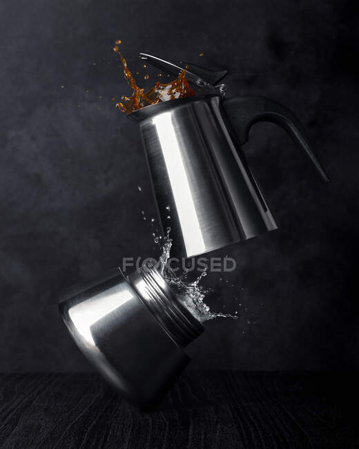 Vue du dessus de la cafetière en acier inoxydable avec éclaboussure d'eau et boisson chaude sur fond sombre — Photo de stock