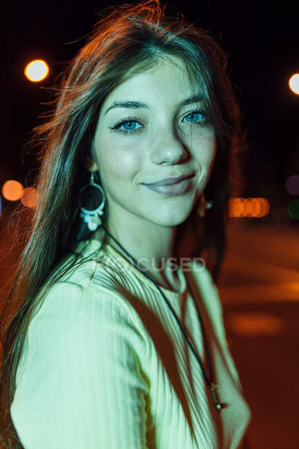 Seitenansicht einer charmanten jungen Frau mit langen Haaren, die in der Abendstadt gegen die Fahrbahn blickt — Stockfoto
