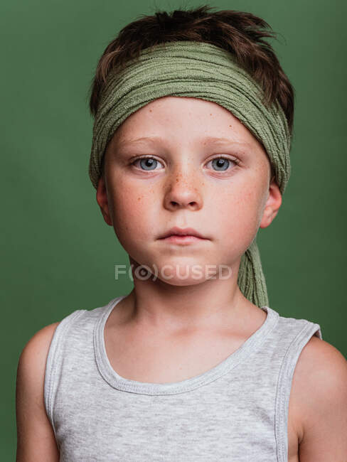 Alegre preteen karatê menino em hachimaki lenço de cabeça de pé no fundo verde no estúdio e se divertindo — Fotografia de Stock