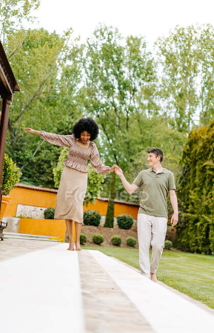 Mulher negra andando ao longo de degraus de pedra de varanda de casa de campo e equilíbrio, segurando a mão do homem amoroso — Fotografia de Stock