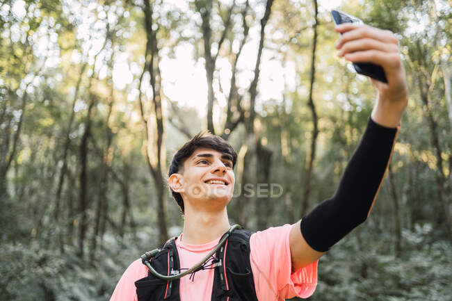Conteúdo caminhante masculino com mochila tomando selfie enquanto viaja — Fotografia de Stock