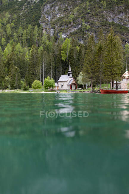 Vista panoramica sul lago Braies con acqua blu e chiesa situata sulla riva delle Dolomiti — Foto stock