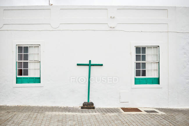 Simple green cross installed on pavement outside white church building on town street in Fuerteventura, Spain — Stock Photo