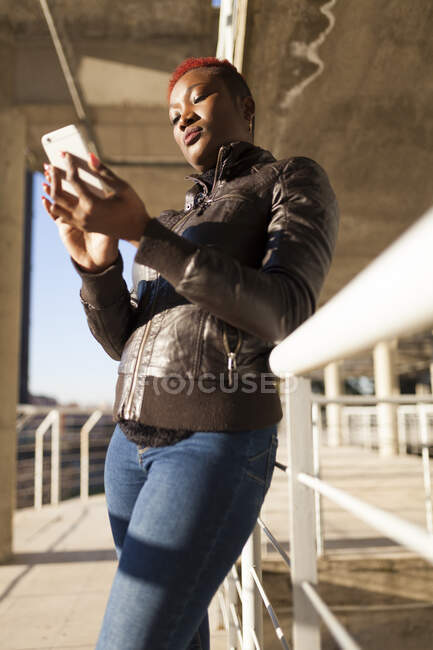 Desde abajo hermosa mujer Afro comunicarse con su teléfono inteligente - foto de stock