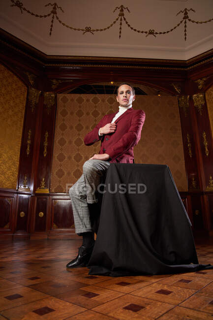Элегантный стильный театральный мужчина в костюме в студии в стиле ретро смотрит в камеру — стоковое фото