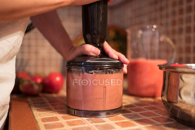 Crop anonymous housewife blending tomatoes in blender while preparing marinara sauce in kitchen at home — Stock Photo