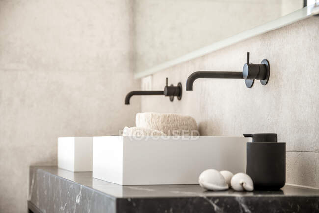 Modernos lavabos dobles blancos en baño con grifos negros diseñados en estilo minimalista en apartamento - foto de stock