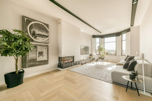 Сучасний інтер'єр просторої вітальні зі зручним диваном і каміном в квартирі, спроектованій в мінімальному стилі — стокове фото
