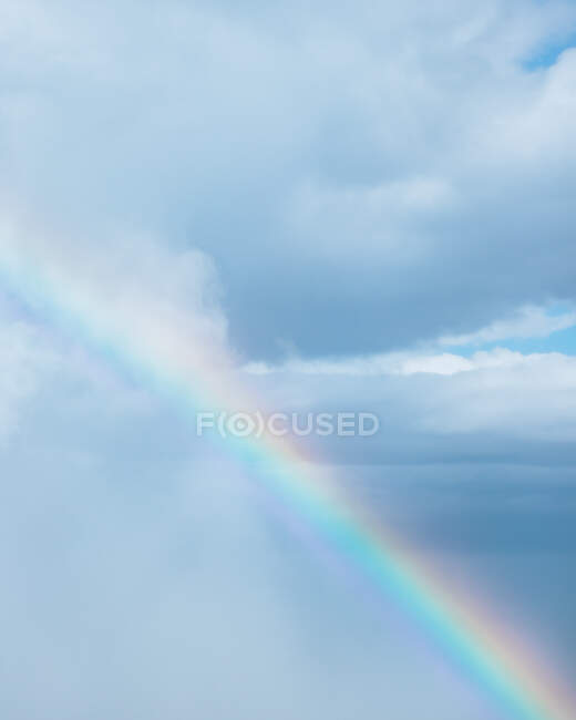 Величественный вид дрона на красочную радугу в голубом небе с облаками в дневное время — стоковое фото