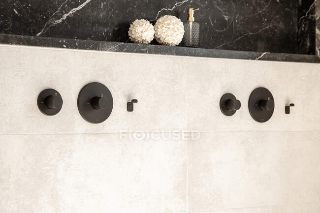 Black faucet handles on while tile wall in modern bathroom in minimal style — Stock Photo