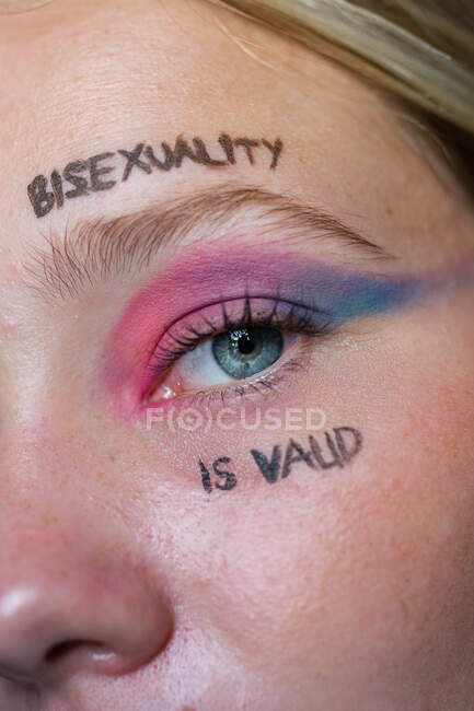 Lesbienne femelle avec inscription sur le visage La bisexualité est valide en regardant la caméra — Photo de stock