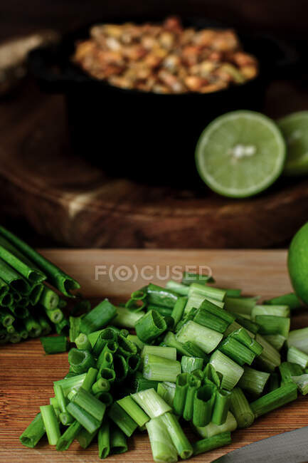 Купка зрізаної свіжої зеленої цибулі, розміщеної на дерев'яній обробній дошці на внутрішній кухні — стокове фото