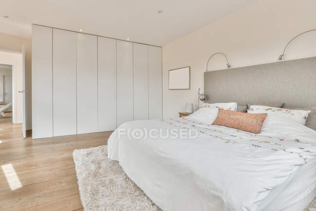 Intérieur de la chambre lumineuse avec des murs blancs meublés avec lit et armoire dans une maison moderne de style loft — Photo de stock