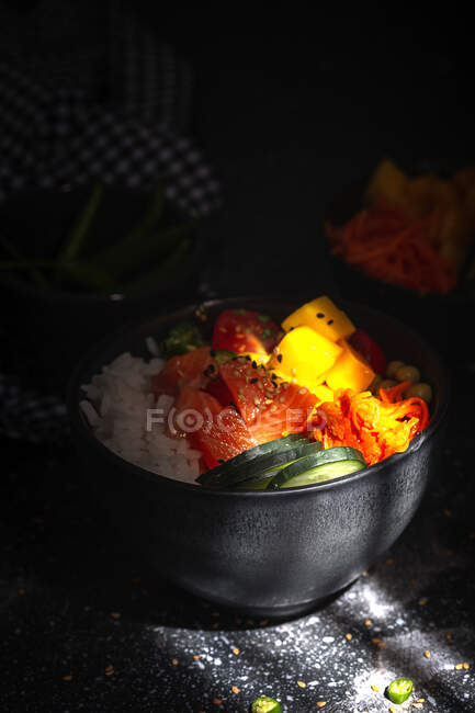 Alto ángulo de empuje asiático con salmón y arroz con verduras variadas servidas en tazón en la mesa en el restaurante - foto de stock