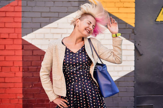 Безтурботний альтернативний жіночий кидання фарбованого короткого волосся на барвисту стіну в міській місцевості — стокове фото