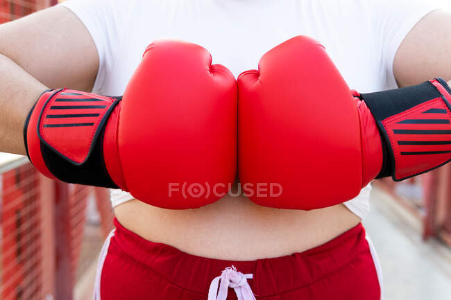 Combatiente irreconocible en envolturas de muñeca y guantes de boxeo golpeando puños durante el entrenamiento durante el día - foto de stock