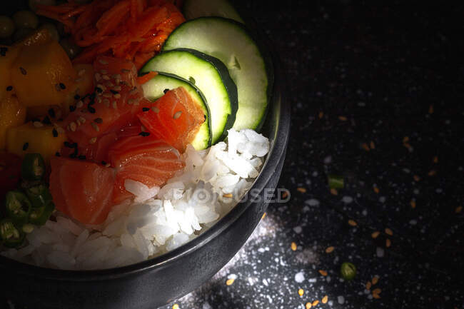 High angle of Asian poke with salmon and rice with assorted vegetables served in bowl on table in restaurant — Stock Photo