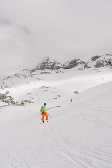 Atleta anónimo sobre esquís en Pico AunAmendi en Pirineos nevados Montañas bajo cielo nublado en Navarra España - foto de stock