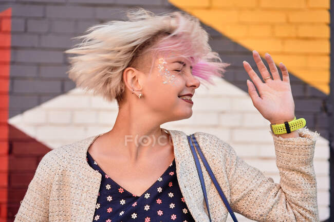 Беззаботная альтернатива женщина бросает короткие волосы на красочные стены в городской местности — стоковое фото
