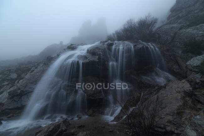 Spettacolare veduta delle cascate con puri fluidi acquatici sul monte sotto il cielo nebbioso in autunno — Foto stock