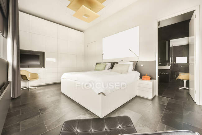 Spacious light bedroom with queen size bed and attached bathroom in modern loft style apartment with white walls and marble floor — Stock Photo