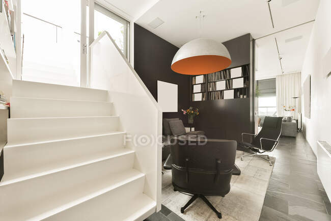 Дизайн інтер'єру вітальні з зручним диваном і шкіряним кріслом в сучасній квартирі з білими і чорними стінами — стокове фото