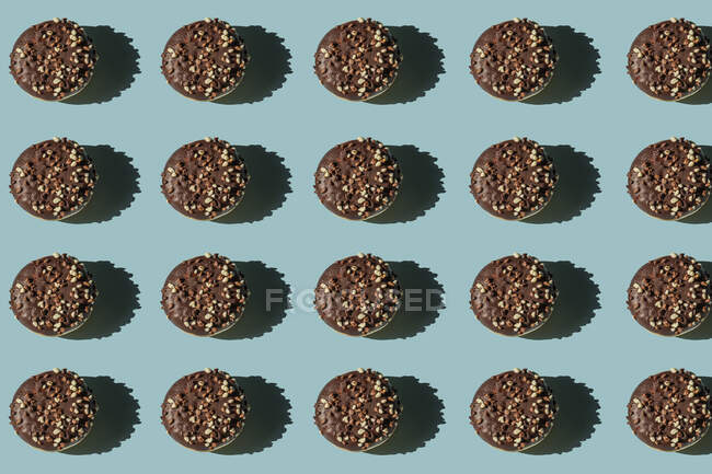 Vista superior de muchos donuts sin agujero cubierto con chocolate y nueces sobre fondo azul - foto de stock