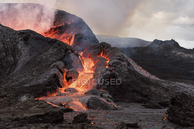 Malerischer Blick auf den Fagradalsfjall mit schnellem Feuer und Lava unter diffundierendem Rauch in Bergen mit Wolken in Island — Stockfoto