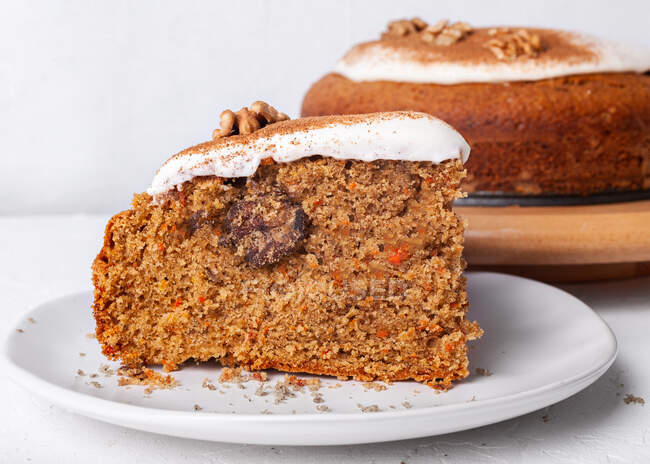 Savoureux morceau de gâteau à la carotte avec de la noix et de la cannelle en poudre sur glaçage sucre sur fond clair — Photo de stock