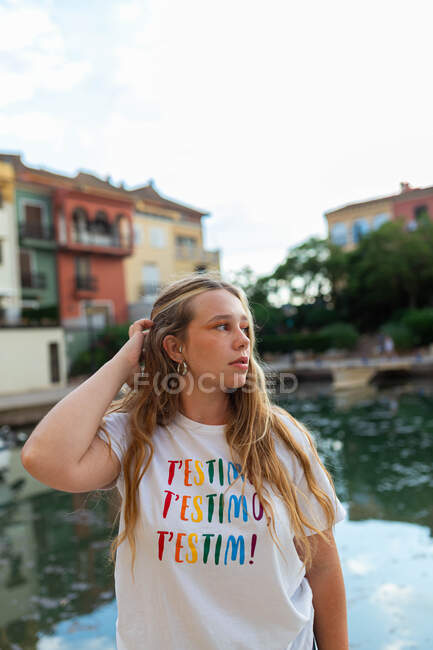 Tranquilo jovem do sexo feminino com cabelos longos em pé em aterro na cidade tropical na noite de verão — Fotografia de Stock