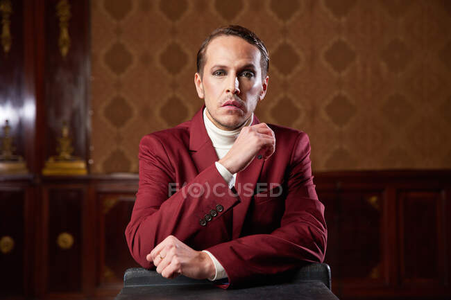 Serious pensive adult male theater artist with makeup and in elegant outfit looking at camera while thinking over decision — Stock Photo