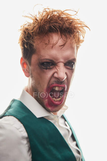 Ексцентричний чоловічий актор з матовим макіяжем, що кричить з гнівом під час виступу на білому тлі — стокове фото