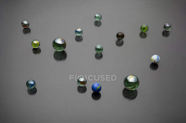 From above backdrop of collection of decorative glass beads with ornament reflecting on gray surface — Stock Photo